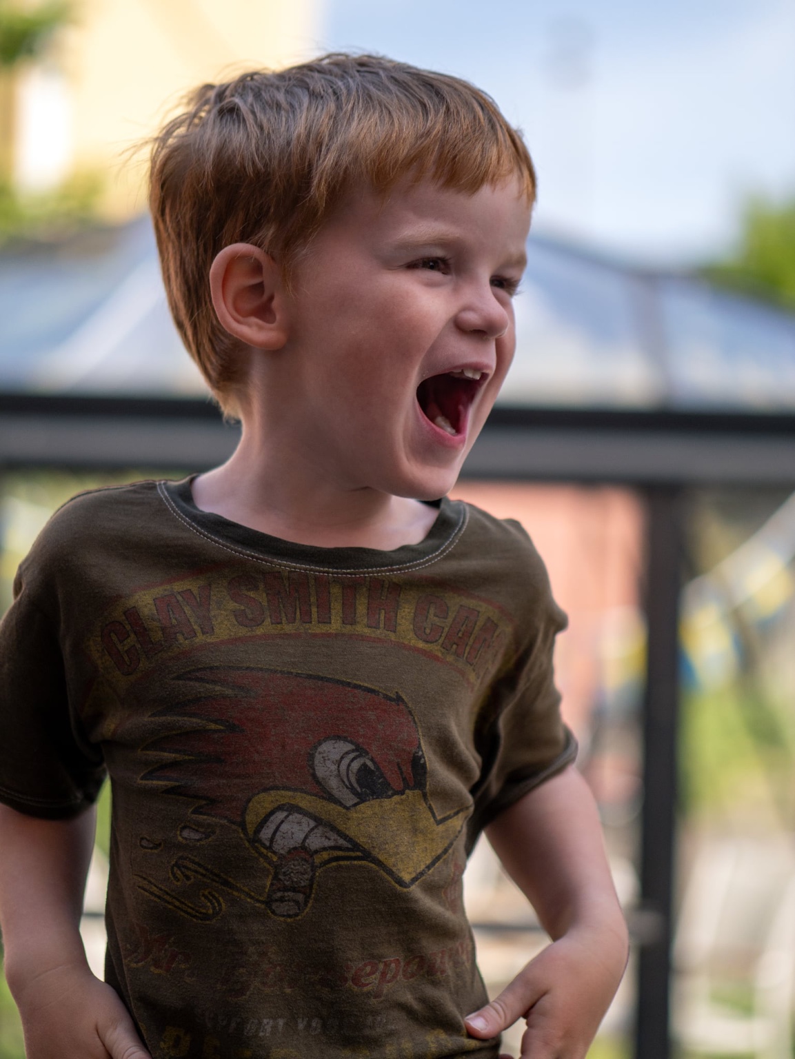 Barn i mörk t-shirt skrattar utomhus