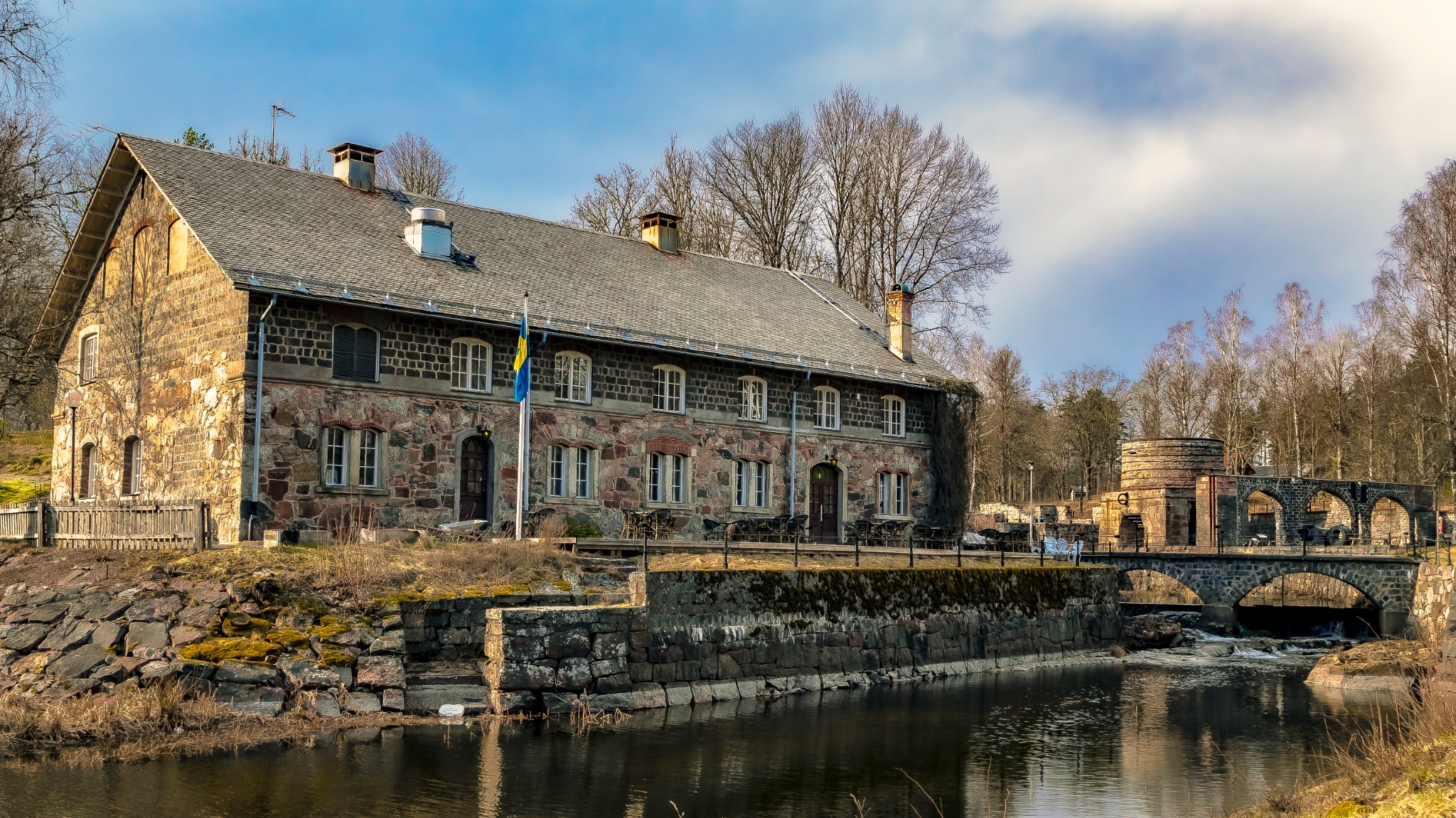 Stor stenbyggnad och stenvalvsbro vid ett vattendrag